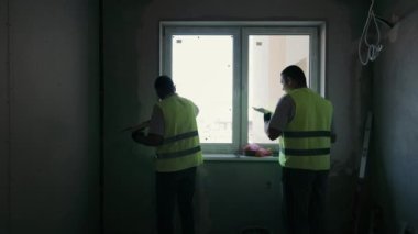 İç yapı işe yarıyor. Pencerenin kenarına duvarları yapıştıran iki zanaatkarın silueti.