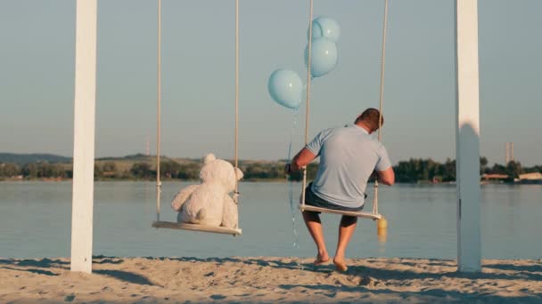 ชายท โดดเด ยวพร อมก บหม และล กบอลพองน งบนแกว งใกล ทะเลสาบ — วีดีโอสต็อก
