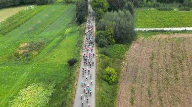 Bisikletçilerin bir pelotonu kırsalda keskin bir viraja giriyor. Bir grup bisikletçi tarafından bisikletle maraton mesafesi aşılıyor.