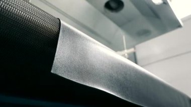 Lastik paspas üretimi. Işıkta parlayan bir lastik parçası basından beslenir.