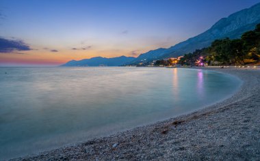 Hırvatistan 'ın Dalmaçya kentindeki Baska Voda' da gün batımında boş plajda manzara
