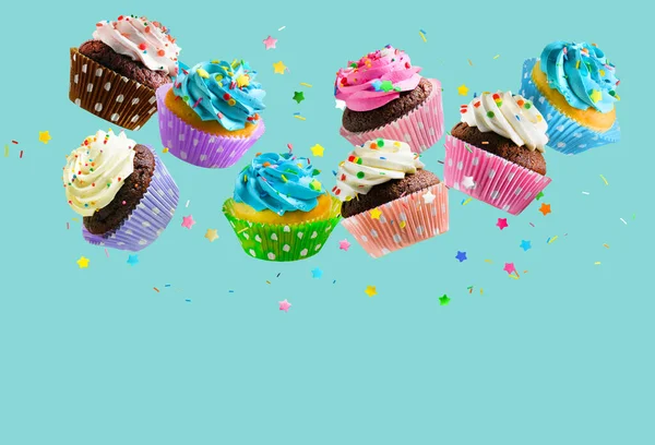 Cupcakes com polvilhas coloridas caindo sobre o fundo azul do aqua. Espaço de cópia — Fotografia de Stock