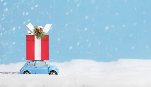 Auto blu con scatola regalo di Natale su un tetto in nevoso giorno d'inverno. — Foto Stock