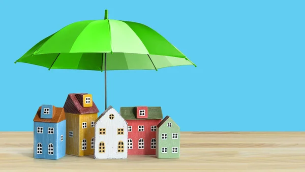 Häuser, die mit Regenschirmen abgedeckt sind. Immobiliensicherheitskonzept. Kopierraum — Stockfoto