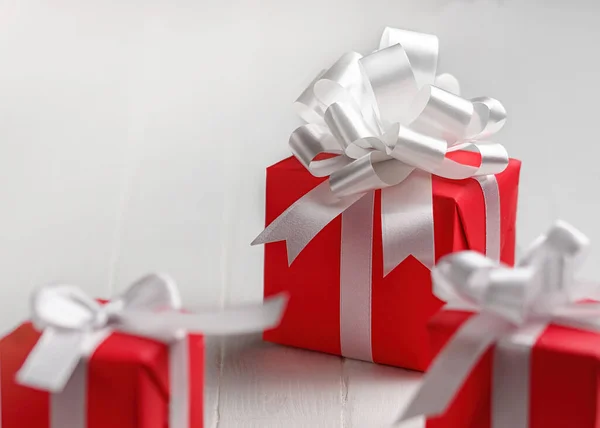 Κόκκινα κουτιά δώρου με λευκό φιόγκο σε λευκό φόντο τραπεζιού. — Φωτογραφία Αρχείου