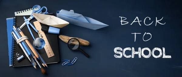 Back to school banner, concept background with lettering on dark blue chalkboard. School supplies on chalkboard background.