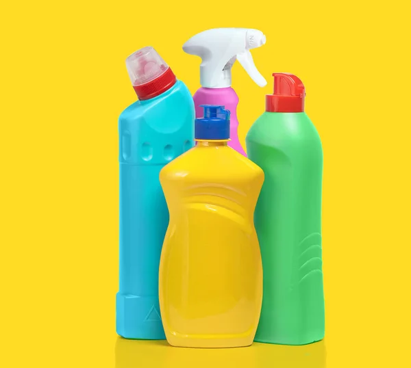 Household cleaning products in plastic bottles isolated on a yellow background. Colorful plastic bottles product mockup.