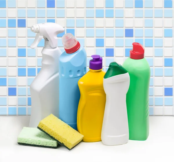 Household cleaning products in plastic bottles on the blue mosaic tile wall background
