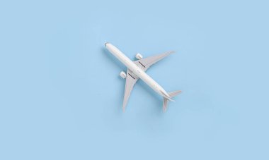 Miniature white toy airplane model on a blue background. Flat lay. Directly above. Modern passenger aircraft