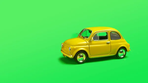 Model yellow retro toy car on green background. Miniature car with copyspace