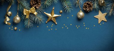 Mavi arka planda köknar dalları, koniler ve altın yıldızlardan oluşan Noel sınır kompozisyonu. Düz konum, üst görünüm, kopyalama alanı