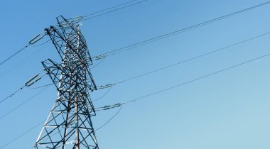 Mavi gökyüzü arka planında yüksek voltaj kabloları olan çelik elektrik direği inşaatı. Boşluğu kopyala