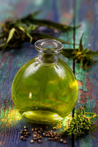 Органическое растительное масло конопли с листьями и семенами на деревянном фоне — стоковое фото