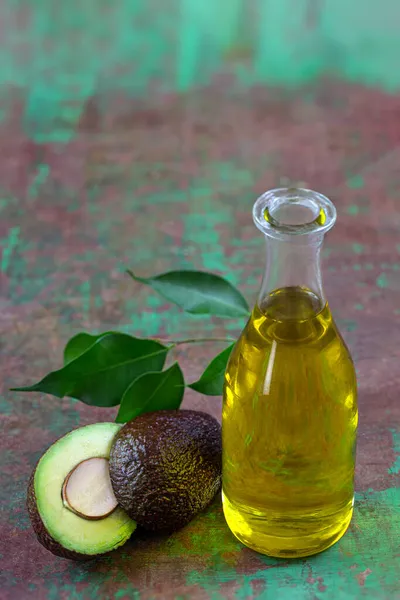 Bouteille d'huile végétale d'avocat avec des fruits coupés en deux — Photo