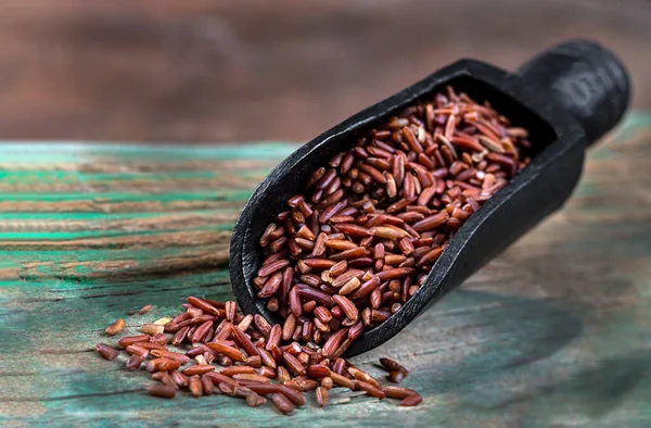 Arroz rojo - Cereales sin gluten en cuchara de madera negra —  Fotos de Stock