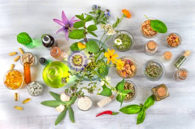 Panoramic, top view of food supplements, capsules, homeopathy, essential oilssurrounded by flowers and plants clipart