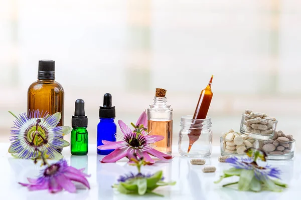 Passionflowers around bottles of vegetable oil, cosmetics, capsules, food supplements