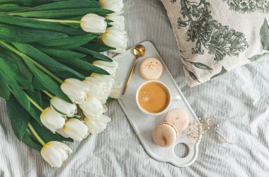 Yatakta kahvaltı, bir fincan kapuçino, çiçekler, bahar, kadınlar günü.