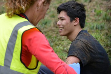 25 Mayıs 2015 'te Brockworth, İngiltere' de Cooper 's Hill' de yapılan geleneksel peynir yuvarlama yarışları sırasında yaralı bir yarışçı sağlık görevlilerinden tedavi görüyor. Onaylanmamış yıllık etkinliğe binlerce kişi katıldı.
