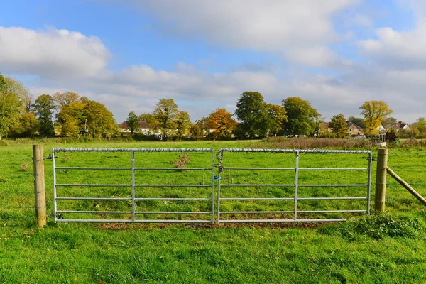 Bir çiftlik kapısı ve yeşil tarlaların manzarası