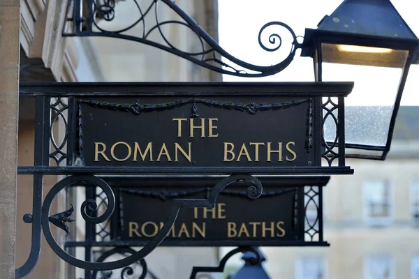 View of Vintage Signs and Street Lamps at the Entrance of the Historic Roman Baths in the City of Bath in Somerset England
