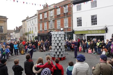 Kalabalık, 1 Mayıs 2022 'de İngiltere' nin Devizes kentinde şehir merkezindeki bir pazar meydanındaki sokak performansını izliyor..