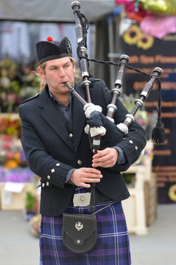 Bath, Uk - 10 Şubat 2016: Geleneksel İskoç kıyafetleri giyen bir adam şehir merkezindeki bir sokakta otobüsle giderken gayda çalıyor. Tarihi Somerset şehir her yıl turist 4 milyondan fazla alır.
