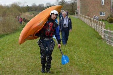 A man carries a kayak after riding the Severn Bore on April 9, 2016 in Minsterworth, UK. The Severn bore is a tidal bore seen on the tidal reaches of the River Severn in southwest England.