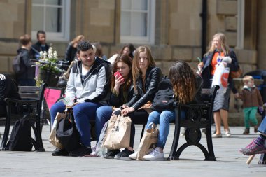People sit on a bench on a street in the city centre on May 3, 2016 in Bath, UK. The beautiful Somerset city is a popular travel destination receiving 4 million tourist visitors each year.