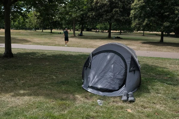 View of a tent on a green lawn in a public park, UK