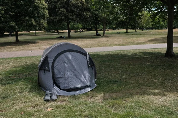 View of a tent on a green lawn in a public park, UK