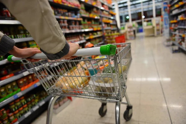 Shopper pushes a cart in supermarket aisle - image has shallow depth of field with intentional blur