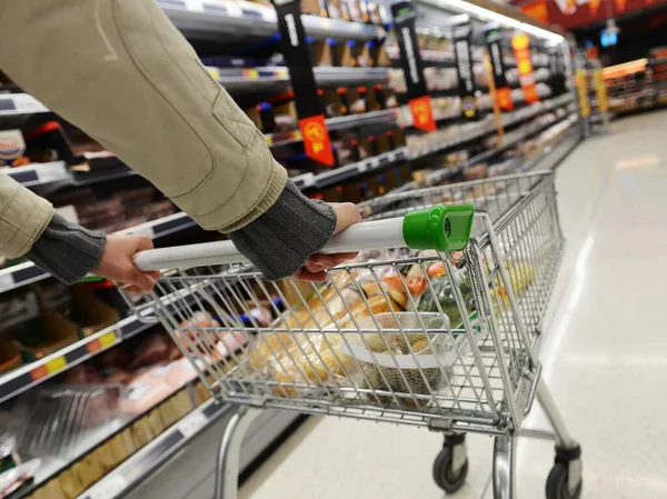 Shopper pushes a cart in supermarket aisle - image has shallow depth of field with intentional blur
