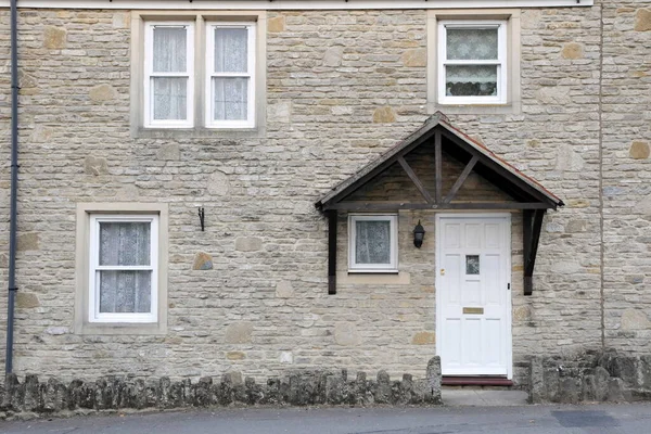 Exterior view of a traditional stone cottage house on the street in an English town