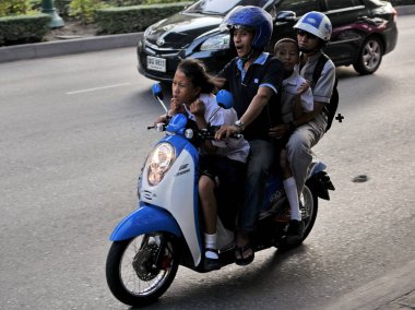 20 Mayıs 2011 'de Bangkok, Tayland' da akşam trafiği sırasında motosikletle aile seyahati. Aile ulaşımı için motosiklet kullanımı Tayland başkentinde yaygındır..