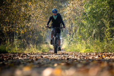 Kız sonbahar parkında bisiklet sürüyor.