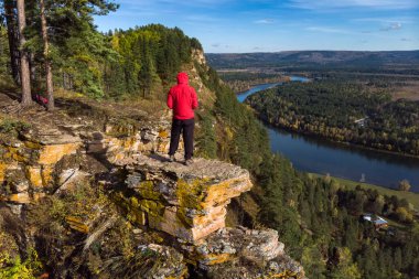 Bir adam uçurumun kenarında durur ve nehrin manzarasına hayran kalır.