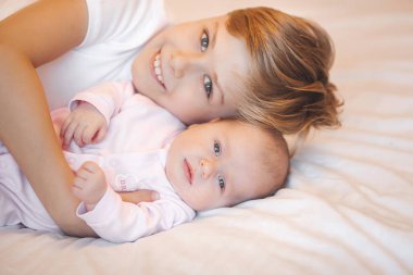 Küçük erkek kardeş yeni doğmuş kız kardeşini tutuyor. Bebek ve çocuk içeride..