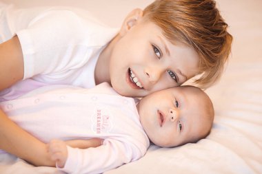 Küçük erkek kardeş yeni doğmuş kız kardeşini tutuyor. Bebek ve çocuk içeride..