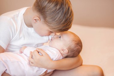 Küçük erkek kardeş yeni doğmuş kız kardeşini tutuyor. Bebek ve çocuk içeride..