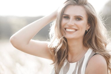 Beautiful blond woman closeup portrait outdoors. Smiling face. Lovely lady at summer background. Emotional female outdoors.