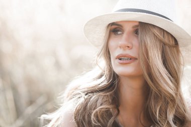 Young attractive woman in the hat. Closeup portrait of beautiful woman outdoors. Pretty lady smiling
