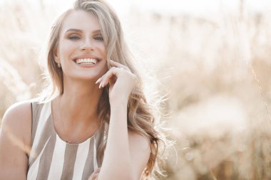 Beautiful blond woman closeup portrait outdoors. Smiling face. Lovely lady at summer background. Emotional female outdoors.