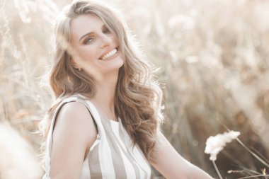 Beautiful blond woman closeup portrait outdoors. Smiling face. Lovely lady at summer background. Emotional female outdoors.