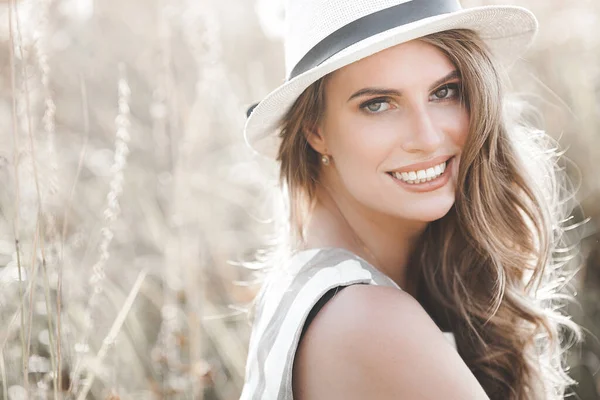 Young attractive woman in the hat. Closeup portrait of beautiful woman outdoors. Pretty lady smiling