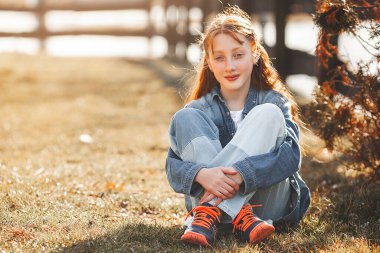 Açık havada güzel, kızıl saçlı bir kız. Gençlik portresi. Parktaki neşeli genç kız..