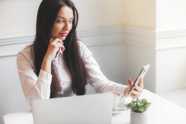 Kafeteryada dizüstü bilgisayarla yazı yazan çekici genç bir kadın. Esmer, içeride, aletlerle..