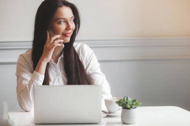 Kafeteryada dizüstü bilgisayarla yazı yazan çekici genç bir kadın. Esmer, içeride, aletlerle..