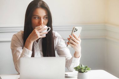 Kafeteryada dizüstü bilgisayarla yazı yazan çekici genç bir kadın. Esmer, içeride, aletlerle..