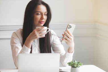 Kafeteryada dizüstü bilgisayarla yazı yazan çekici genç bir kadın. Esmer, içeride, aletlerle..